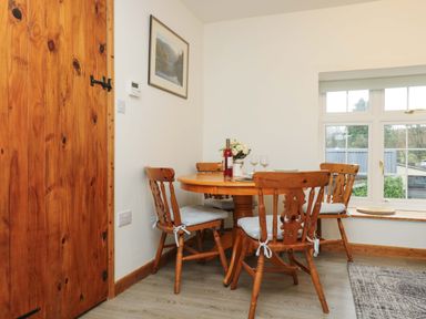 A dining area with a round wooden table and four wooden chairs near a window at Cheesewring Cottage in Minions near Upton Cross