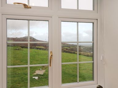 A window with raindrops showing a green field and hills at Cheesewring Cottage in Minions near Upton Cross
