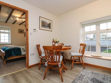 A dining area with a round wooden table and four wooden chairs near a window at Cheesewring Cottage in Minions near Upton Cross