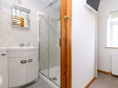 A bathroom with a shower cubicle, a sink with a vanity unit, and a wall-mounted mirror at Cheesewring Cottage in Minions near Upton Cross