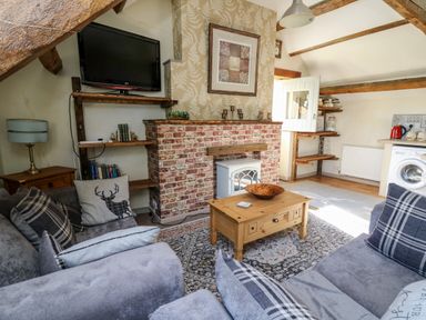 A living room with grey sofas and a wooden coffee table near a brick fireplace and shelves at The Cheese Loft in White Mill near Carmarthen