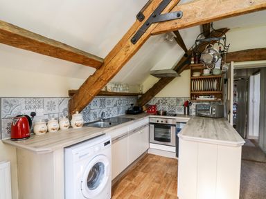 A kitchen with wooden beams washing machine oven and countertop at The Cheese Loft in White Mill near Carmarthen