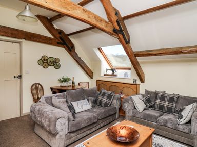 A living room with two grey sofas and wooden beams at The Cheese Loft in White Mill near Carmarthen
