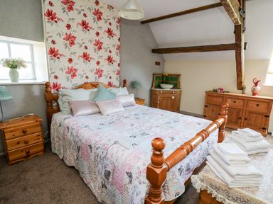 A bedroom with a wooden bed and floral wallpaper at The Cheese Loft in White Mill near Carmarthen