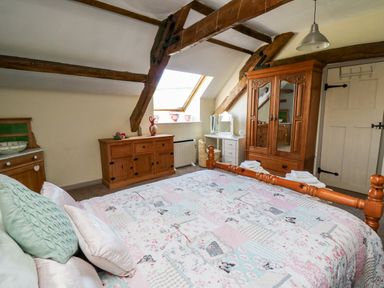A bedroom with wooden furniture and exposed beams at The Cheese Loft in White Mill near Carmarthen