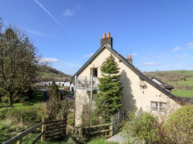A countryside house with a balcony and trees around at The Cheese Loft in White Mill near Carmarthen