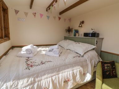 A bedroom with a decorated bed a green armchair and a radio on a shelf at Tawny in Morchard Bishop