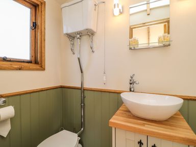 A bathroom with a high-level toilet cistern a wooden countertop basin under a mirror at Tawny in Morchard Bishop