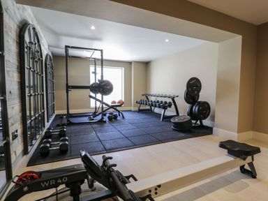 A home gym room with weightlifting equipment dumbbells and a workout bench at Farmyard House Llanfechell