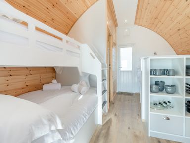 A bedroom with a white bunk bed and shelves with kitchenware at Carlton Manor Pod 1 in Aldbrough