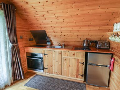 A wooden kitchen with oven sink refrigerator and kettle at Pine Lodge in Llanddeusant near Llandovery