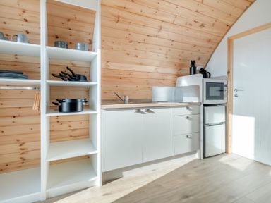 A kitchen with wooden walls white open shelves and cabinets with a microwave and mini fridge at Carlton Manor Pod 2 in Aldbrough