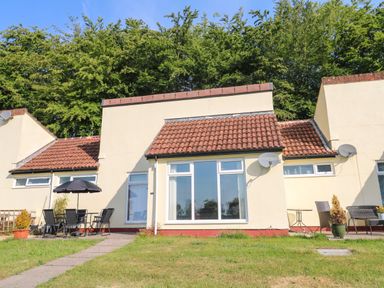 Exterior view of a bungalow with lawn and patio furniture at 39 Manorcombe Bungalows Honicombe Holiday Village near Drakewalls