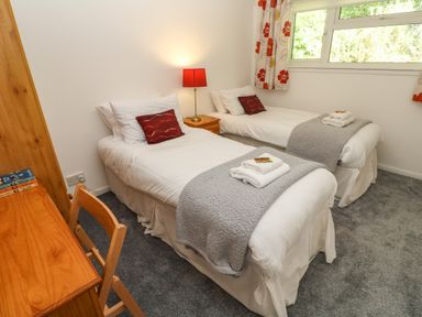 A bedroom with two single beds a wooden desk and chair and a window at 39 Manorcombe Bungalows Honicombe Holiday Village near Drakewalls