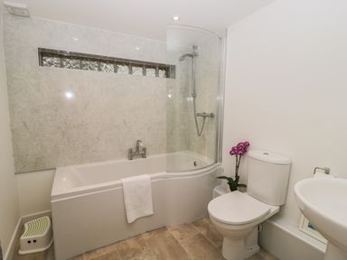 A bathroom with a bathtub and shower next to a toilet and sink at Brimley Barn in Kittisford near Milverton