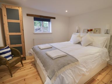 A bedroom with a double bed and towels on a gray throw at Brimley Barn in Kittisford near Milverton