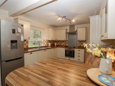 A kitchen with wooden countertops cabinets a stainless steel refrigerator and a vase with yellow flowers at Heathfield in Milverton