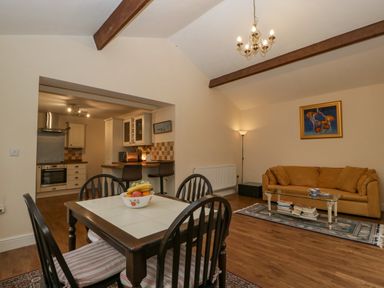 A dining area with a table and chairs near a kitchen with stools and a living room with a sofa and coffee table at Heathfield in Milverton