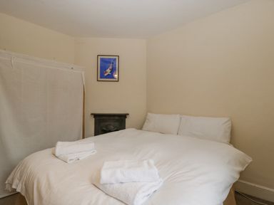 A bedroom with a double bed with white bedding and folded towels and a framed picture on the wall at Heathfield in Milverton
