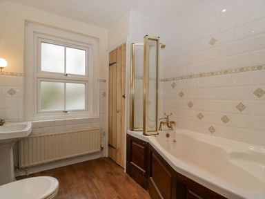 A bathroom with a bathtub a sink a toilet a wooden door and a window at Heathfield in Milverton