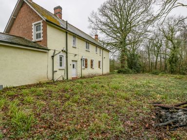 An exterior view of a two story house with a grassy yard and trees in the background at Heathfield in Milverton