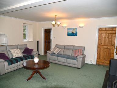 A living room with two leather sofas a round wooden coffee table and wooden doors at Heathfield in Milverton
