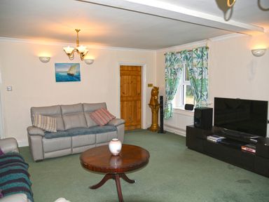 A living room with leather sofas a round wooden coffee table and a large flat screen TV at Heathfield in Milverton