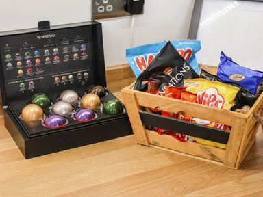 A box of Nespresso coffee capsules and a wooden crate filled with snack packets on a wooden countertop at The Old Police House in Withernsea