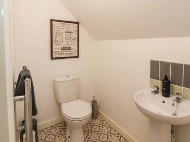 A bathroom with a toilet a sink a towel rail and a framed sign on the wall at The Old Police House in Withernsea