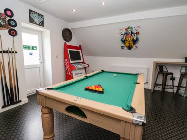 A game room with a pool table a retro arcade machine pool cues and stools at The Old Police House in Withernsea