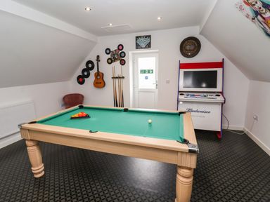 A game room with a pool table guitar wall decor and an arcade machine at The Old Police House in Withernsea