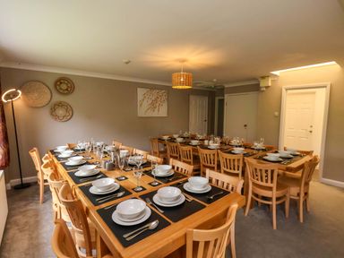 A dining room with a long table set for a meal at Hazelgarth House in Hunmanby