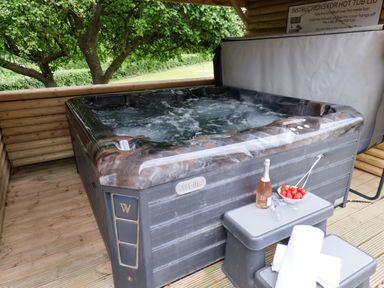A hot tub with a side table holding wine and strawberries at Hazelgarth House in Hunmanby
