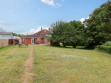 A garden with grass, trees and a house at Hazelgarth House in Hunmanby