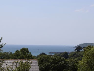 A coastal view with trees in the foreground a roof a pier and the sea at Little Pip in Gulval