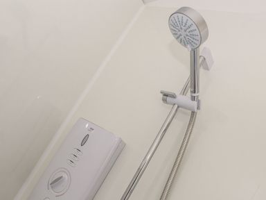 A showerhead with adjustable holder and control panel on a wall at Little Pip in Gulval