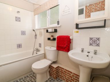 A bathroom with a bathtub shower toilet red towel and pedestal sink at Valley Lodge 55 Callington near Gunnislake