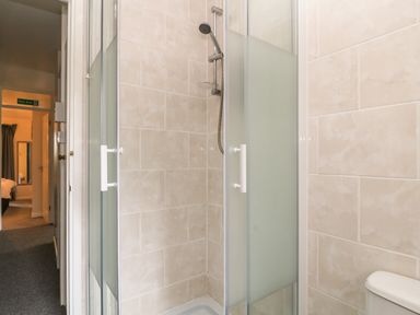 A shower enclosure with frosted glass doors in a tiled bathroom with a toilet partially visible at Valley Lodge 55 in Callington near Gunnislake
