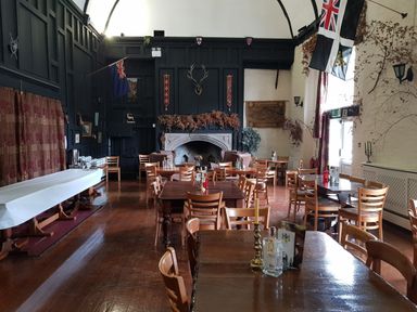 An interior dining room with wooden tables and chairs a fireplace and flags on the wall at Valley Lodge 55 Callington near Gunnislake
