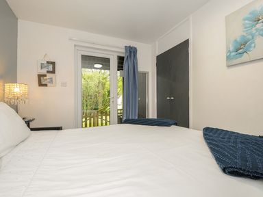 A bedroom with a bed and blue towels near glass doors and a wardrobe at Valley Lodge 55 in Callington near Gunnislake
