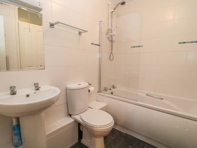 A bathroom with a sink, toilet, bathtub with shower, and a mirror at Valley Lodge 33 Callington near Gunnislake