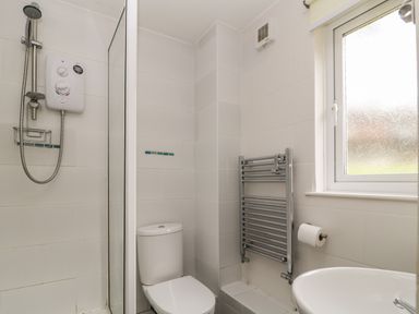 A bathroom with a shower, toilet, heated towel rail, window, and sink at Valley Lodge 33 Callington near Gunnislake