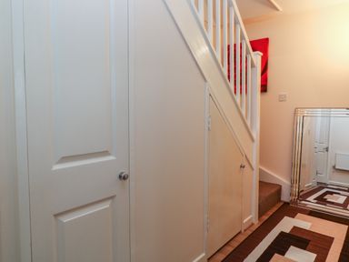 A hallway with white doors a staircase a large mirror and a patterned rug at Valley Lodge 33 Callington near Gunnislake