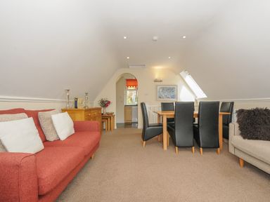 A living room with red and beige sofas a wooden dining table with black chairs and a sideboard at Valley Lodge 33 Callington near Gunnislake