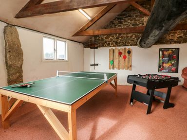A game room with a ping pong table foosball table and wall mounted paddles at Cosy Cottage in Broadwoodwidger near Lifton