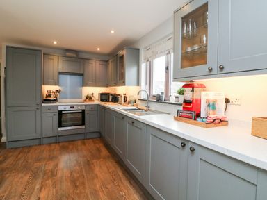 A kitchen with grey cabinets a built in oven a sink and various appliances on the counter at The Old Cowshed in Broadwoodwidger near Lifton