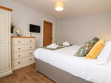 A bedroom with a bed pillows folded towels TV and dresser at The Old Cowshed in Broadwoodwidger near Lifton