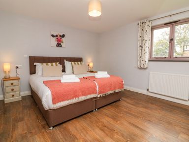 A bedroom with a double bed nightstands with lamps a window and artwork on the wall at The Old Cowshed Broadwoodwidger near Lifton