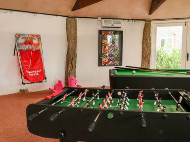 A game room with a foosball table a pool table and a basketball arcade game at The Old Cowshed in Broadwoodwidger near Lifton