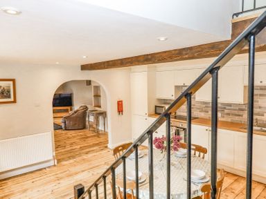 A kitchen and dining area with a table set for four and an arched doorway leading to a living room at Bunts Barn Northlew near Hatherleigh